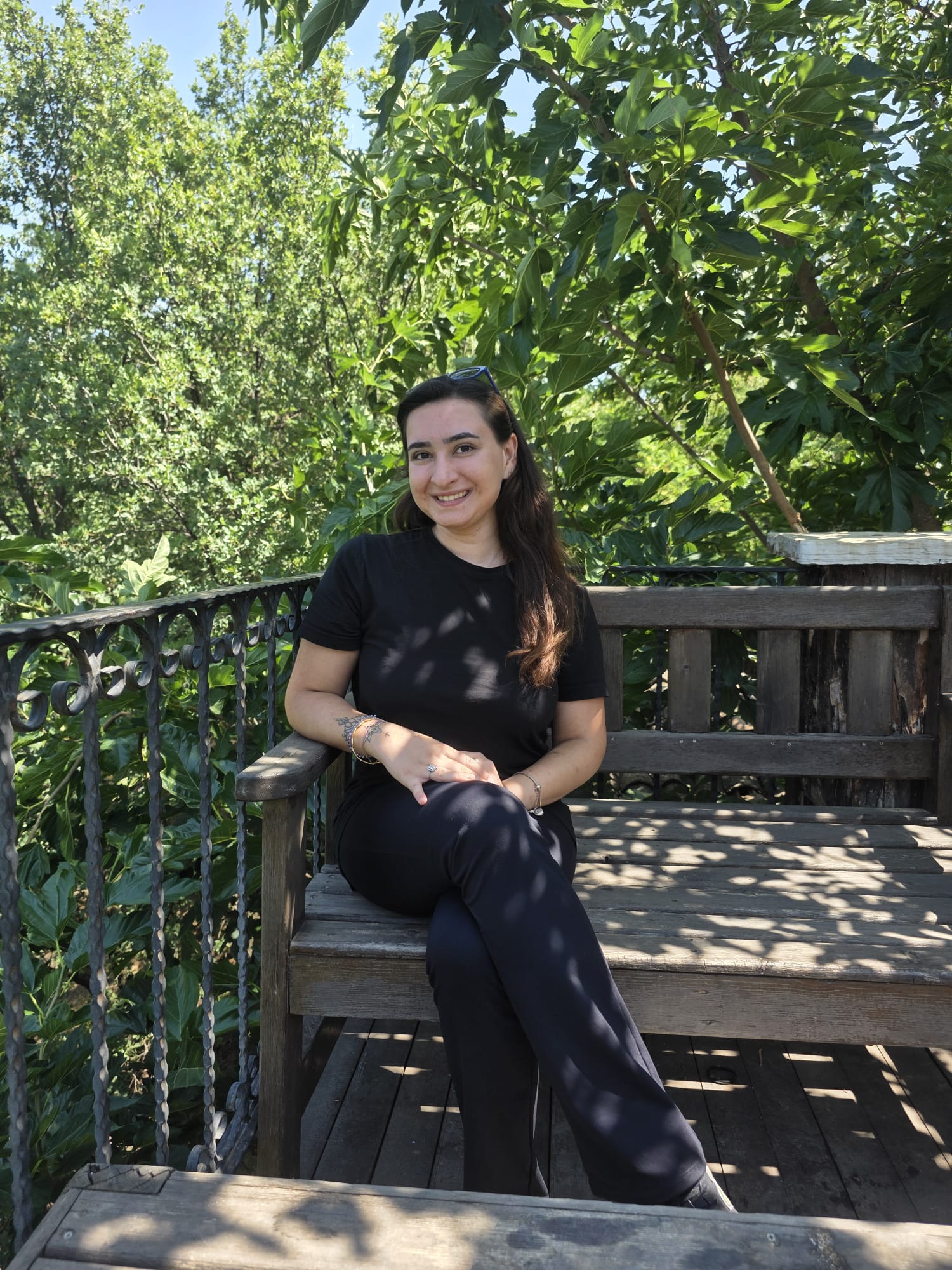Begüm Aydın Ekici, yeşillikler içinde ahşap bir terasta oturuyor